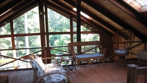 An attic room with wooden floors, a wooden bench, and wicker chairs.