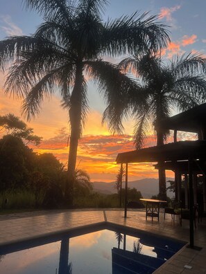 Ein Pool mit Blick auf Palmen und einen Sonnenuntergang.