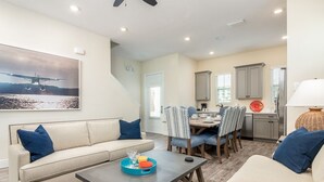 A modern living room with a sofa, coffee table, and dining area with chairs and a table.