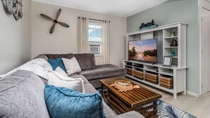 A modern living room with a grey sofa, wooden coffee table, and a white entertainment unit with a TV.