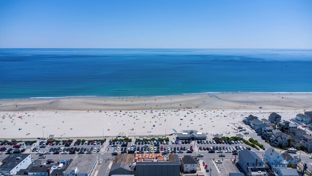 A coastal town with a beach, parking area, and buildings.