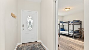 A room with a bunk bed, a door with a glass panel, and a wooden floor. - Heated Pool - 4BR - Sleeps 10 - Pet Friendly (Palm Coast)