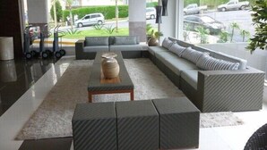 A modern living room with a grey sofa, a coffee table, and a view of the street through large windows. - Luxurious apartment with a 5-star style water park near HOT PARK. (Rio Quente)