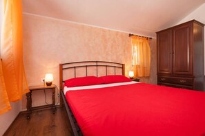 Un dormitorio con una cama grande, mesitas de noche de madera, un armario y cortinas.