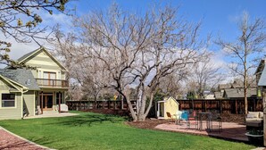 A residential backyard with a lawn, a small shed, and a patio area with outdoor furniture.