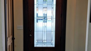 A wooden door with a frosted glass panel, a light fixture above, and a tiled floor.