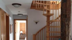 Una scala in legno conduce al secondo piano, un corridoio con porte in legno e un pavimento rivestito di moquette.