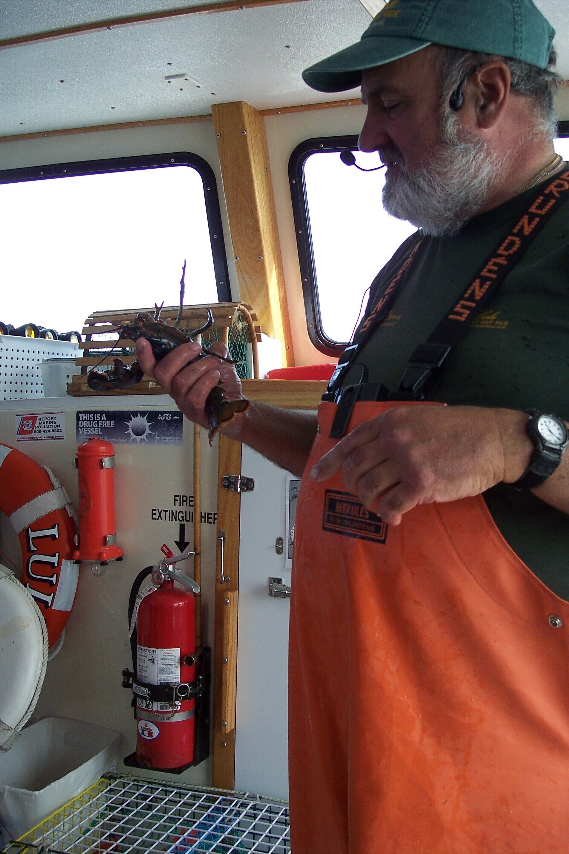 A person holding a crab inside a vehicle with a fire extinguisher and a life buoy visible.