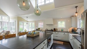 A spacious kitchen with white cabinets, a large island, and pendant lighting. - Katama Luxury - 5+ BR home w/ Heated Pool near the Field Club (Edgartown)