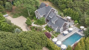 A large house with a swimming pool, surrounded by trees and a well-maintained lawn. - Katama Luxury - 5+ BR home w/ Heated Pool near the Field Club (Edgartown)