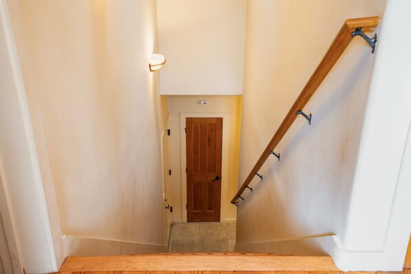 A narrow staircase with a wooden handrail and a wooden door at the top.