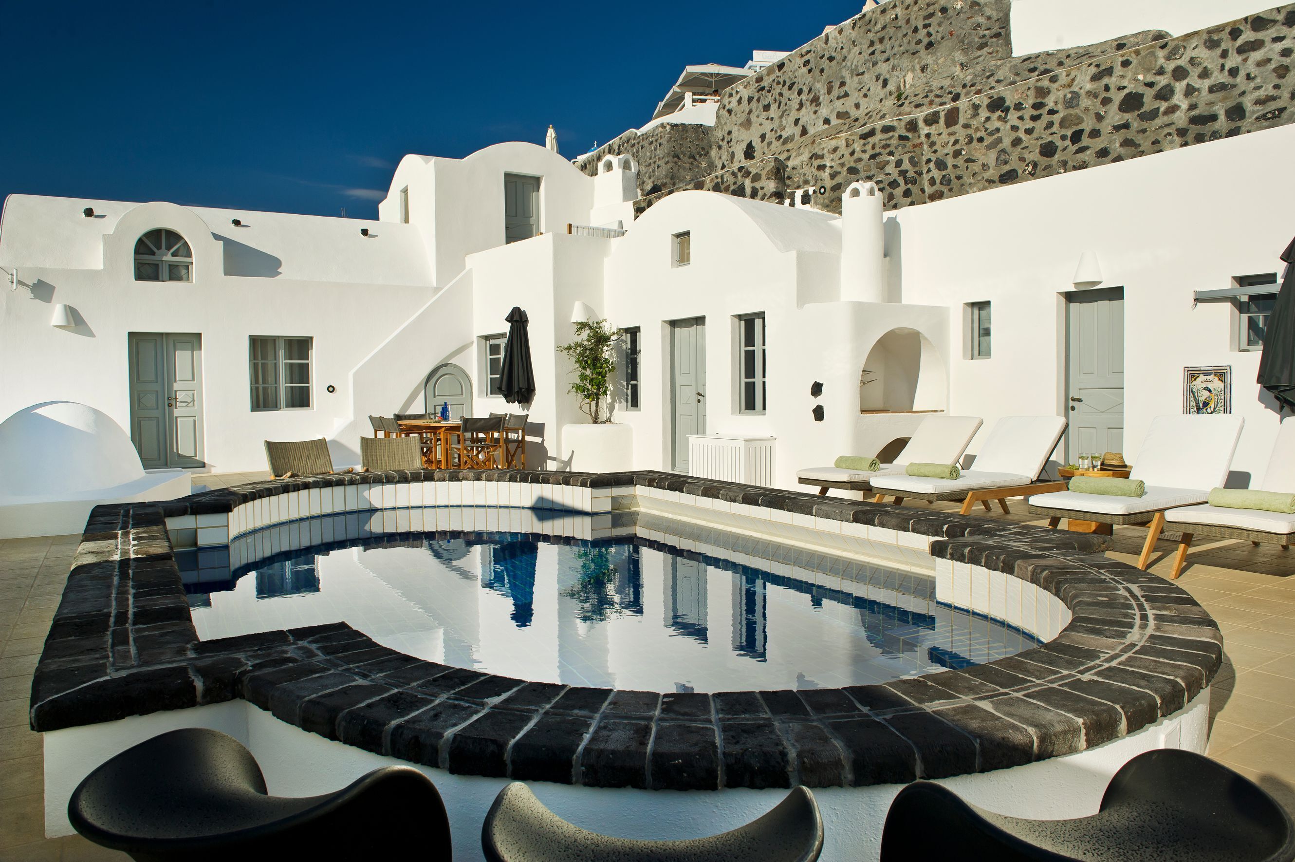 Un espace piscine avec des chaises longues et un mur en pierre.