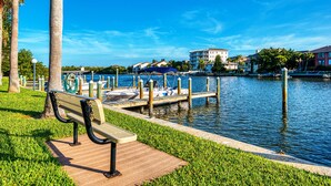A waterfront park with a wooden bench, a dock with boats, and buildings in the background.