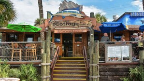 A wooden staircase leading to a restaurant named 'Cottage on the Key' with a sign indicating 'Local World Cuisine'.