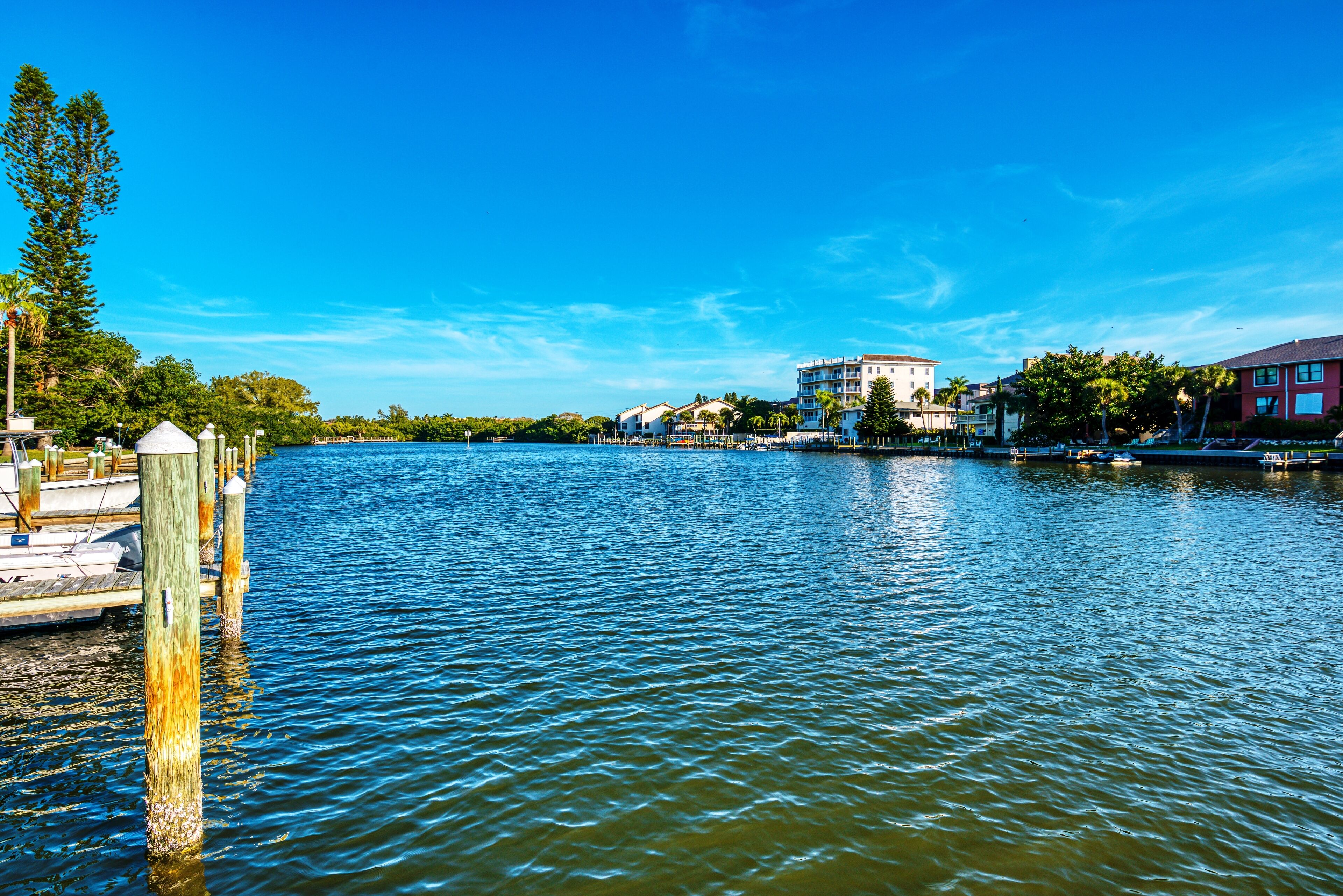 Un hôtel situé au bord de l’eau, doté d’un quai, avec une façade blanche et surplombant un ciel d’un bleu limpide.