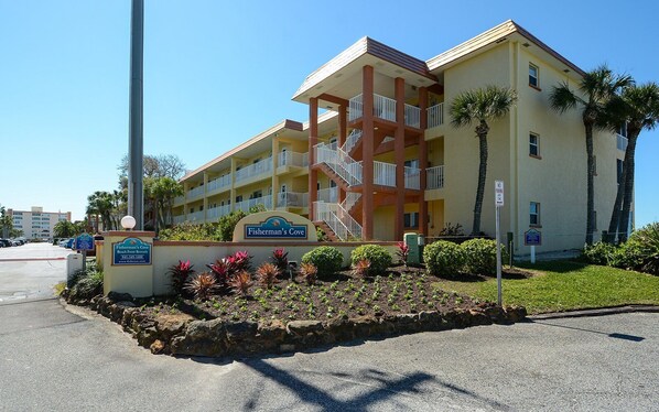 A multi-story hotel with a beachfront view, a sign indicating beachfront rentals, and a parking area. - Beachfront Condo - 3 BR- Heated Pool - Free Boat Docks – Upscale – Siesta Key (Siesta Key)