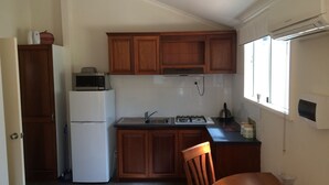 A compact kitchen with wooden cabinets, a refrigerator, a microwave, a sink, and a stove. - North Perth Cottage - Close to city (North Perth)