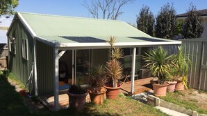 A covered outdoor area with a green roof, surrounded by potted plants and a wooden deck. - North Perth Cottage - Close to city (North Perth)