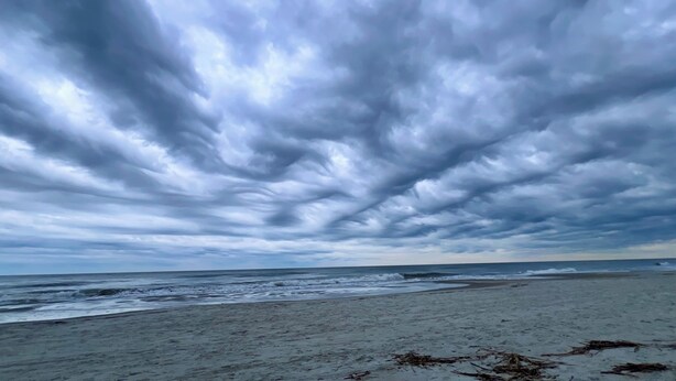 Una playa con una amplia orilla arenosa y un cielo nublado.