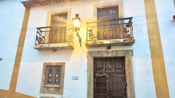 Un edificio con balcón, farol y puerta.