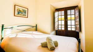 Una cama bien hecha con cabecera, un cuadro en la pared y una ventana con vistas al exterior.