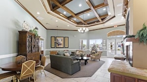 A spacious living room with a high ceiling, wooden beams, a dining area, and a fireplace.