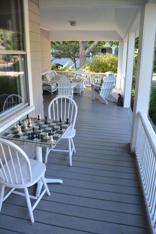 A wooden deck with white chairs and a chess table.