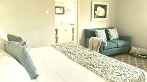 A bedroom with a bed, a sofa, and a bathroom visible through an open door. -  Spacious Oceanview One Bedroom Apartment (Atlantic Shores)
