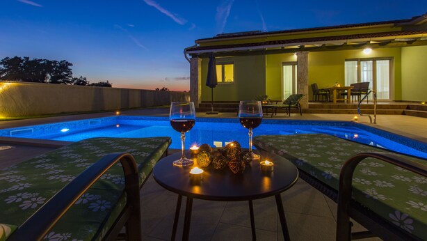 Un espace piscine aménagé sur le toit, avec deux verres de vin rouge, des bougies et une table.
