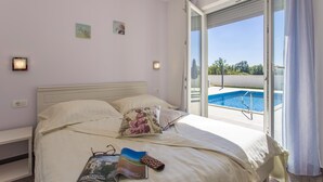 Une chambre avec un lit, une vue sur une piscine et une fenêtre avec des rideaux.