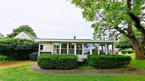 A single-story house with a covered porch, surrounded by well-maintained lawns and hedges.