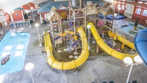 An indoor water park with a pool, slides, and play structures.