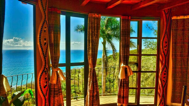 Una habitación con amplios ventanales que dan a una vista panorámica del océano y palmeras.