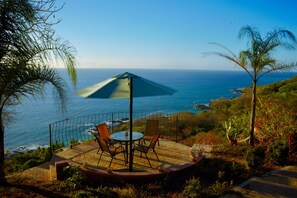 Eine Terrasse mit Tisch und Stühlen mit Blick auf den Ozean.