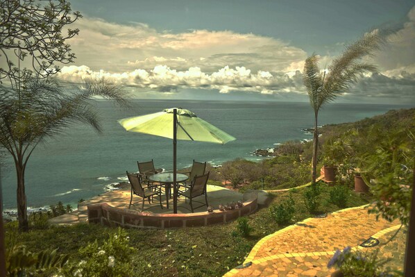 Eine Terrasse mit Tisch und Stühlen mit Blick auf den Ozean.