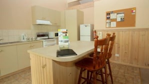 Una cocina con una barra de madera, un refrigerador y un tablón de corcho en la pared.