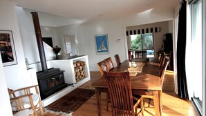 A dining area with a wooden table and chairs, a fireplace, and a view of the outdoors.