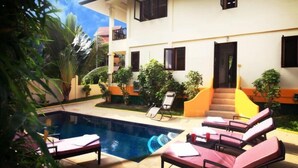A pool area with lounge chairs and a staircase leading to a building.