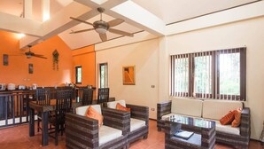 A spacious living area with wicker furniture, a ceiling fan, and large windows.