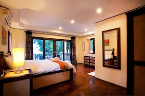 Relax in this serene hotel room with a large bed, dresser, and balcony overlooking the trees.