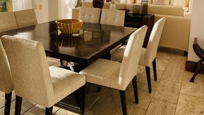 A dining area with a large table, six chairs, and a chandelier. There is a sofa and a painting in the background. - Amazing, Luxury condominium on the 18 hole of Dye Fore  Golf Course (La Romana)