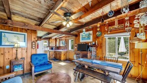 Un intérieur de chalet chaleureux avec des murs en bois, un coin repas, une cuisine et une grande fenêtre.