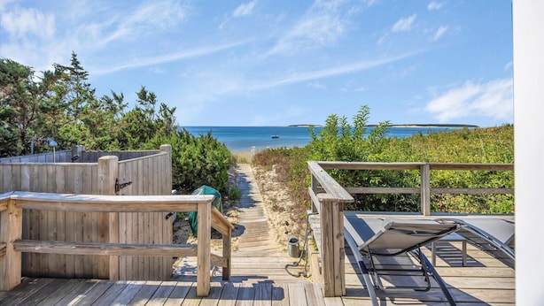 Une terrasse en bois offrant une vue sur la plage et l’océan.