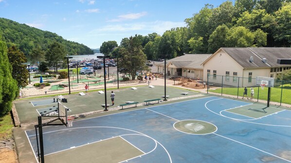 Ein Basketballfeld mit Netz, ein Tennisplatz und ein Gebäude im Hintergrund.