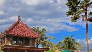 A traditional building with a red tiled roof, surrounded by a well-maintained lawn and palm trees. - Sanur, Elegant 2 Bed Villa
 (Sanur)
