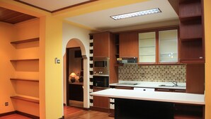A modern kitchen with wooden cabinets, a built-in oven, microwave, and a large island with a sink. - Sanur, Elegant 2 Bed Villa
 (Sanur)