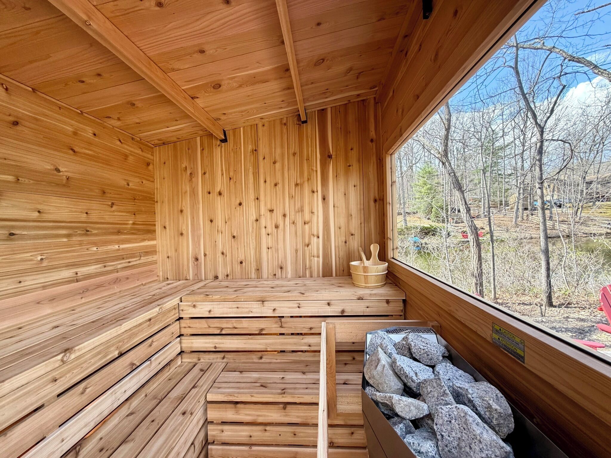 Uma sauna de madeira com bancos e janela com vista para uma paisagem natural.