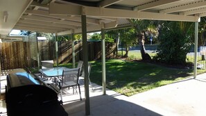 A covered patio with a table and chairs, a grill, and a view of a grassy yard and trees. - Palmgrove 2 - Rainbow Beach. Gorgeous, modern beach escape in a great location. Aircon. Wifi (RAINBOW BEACH)