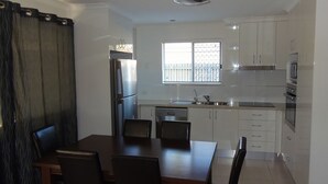 Cocina compacta con comedor, que incluye refrigerador, horno, microondas y pileta.