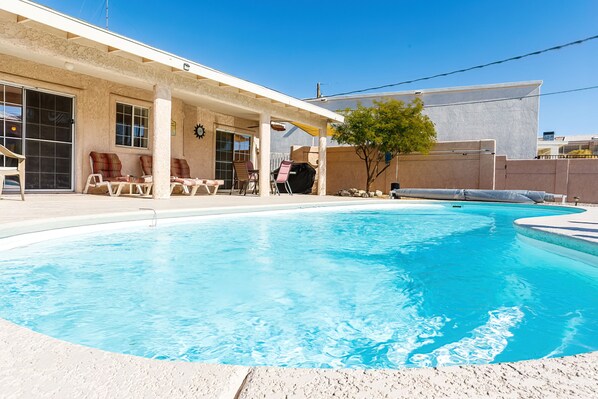 A swimming pool with lounge chairs and a covered patio area. - Spacious, Super Clean, Ping Pong & Alexa music!! (Lake Havasu)